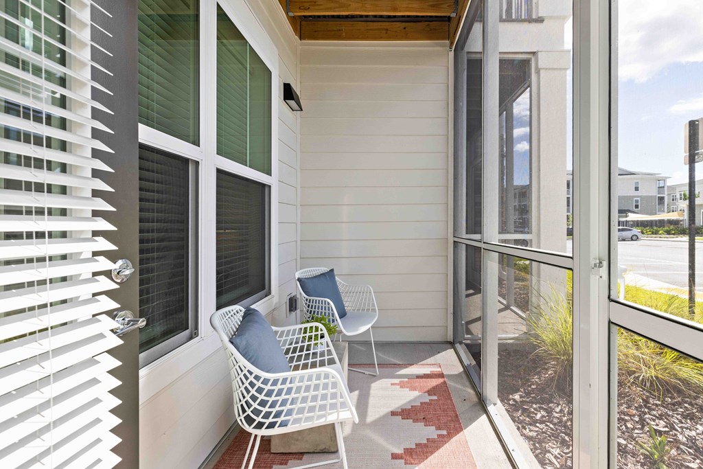 A white chair with a blue pillow is on a porch.