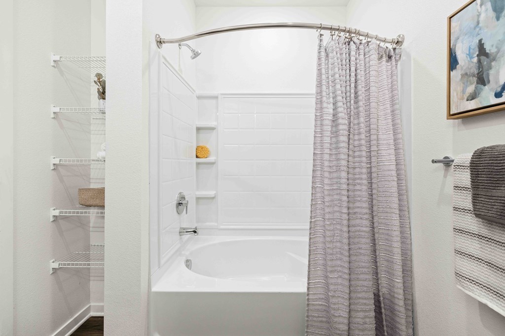 A white bathroom with a shower curtain and a white tub.