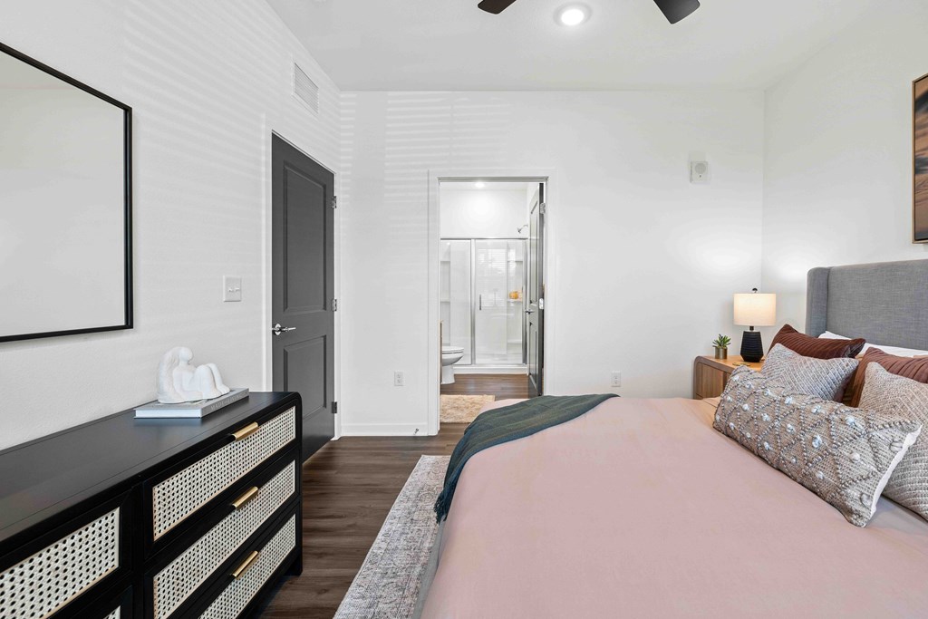 A bedroom with a bed, nightstand, and a painting on the wall.