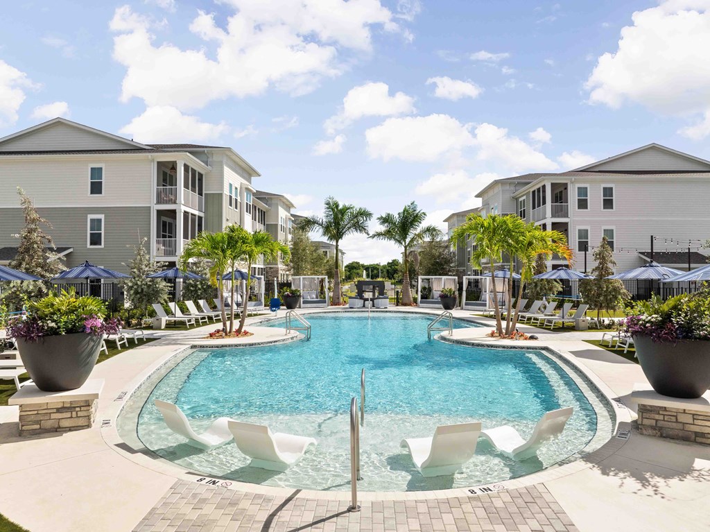 A swimming pool surrounded by white chairs and palm trees.