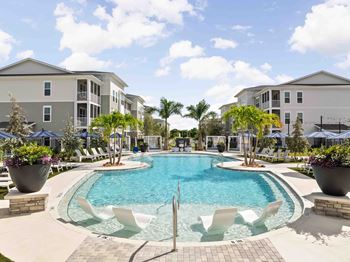 A swimming pool surrounded by white chairs and palm trees.