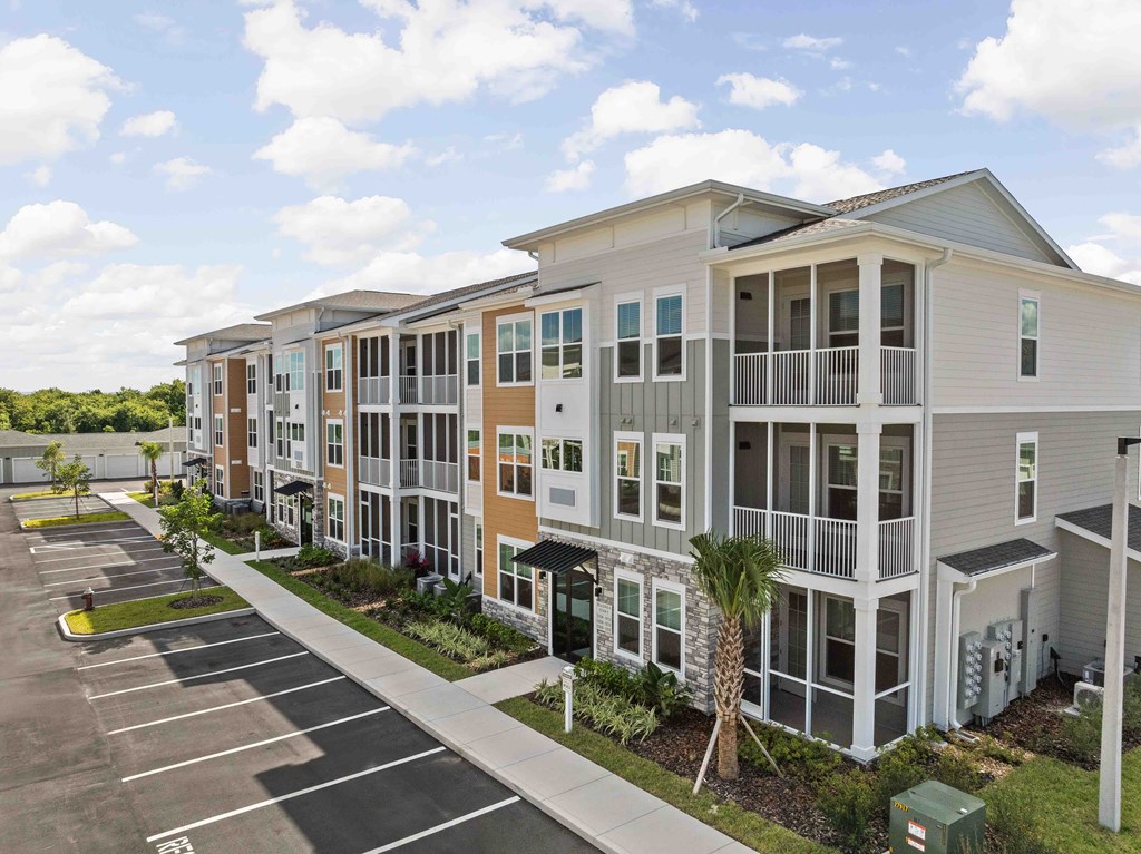 A row of modern townhouses with a parking lot in front.