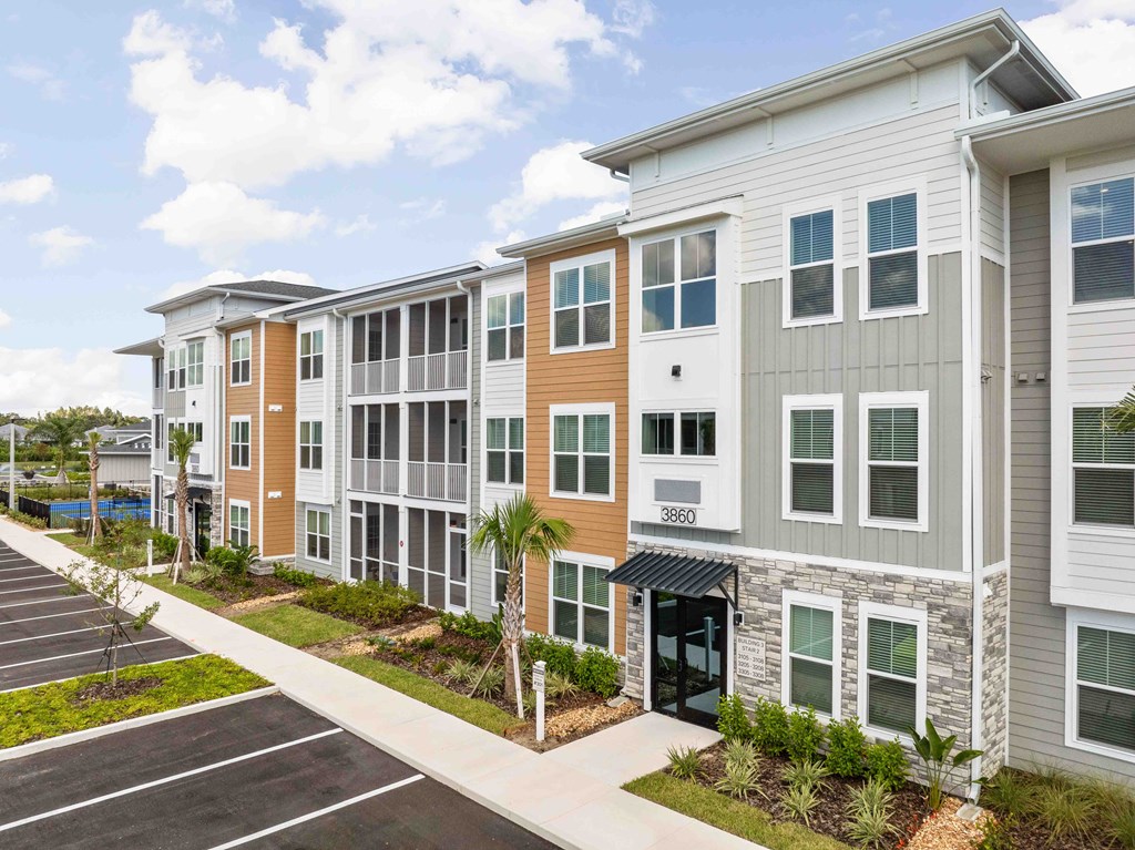 A row of modern townhouses with a parking lot in front.