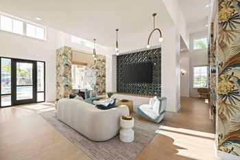 A living room with a white couch and a black TV mounted on the wall.