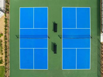 Two tennis courts with blue courts and black surroundings.