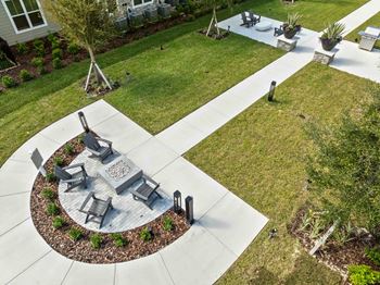 A circular patio with a fire pit and chairs.