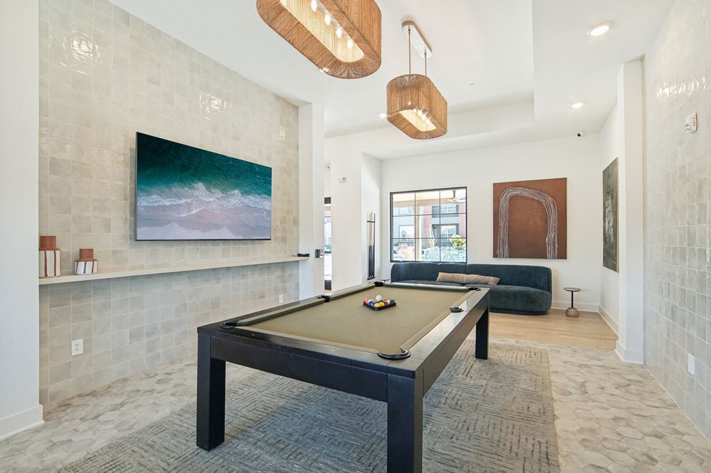 a pool table in a living room with a painting on the wall at The Maddox Luxury Apartment Homes, Buckeye, 85326