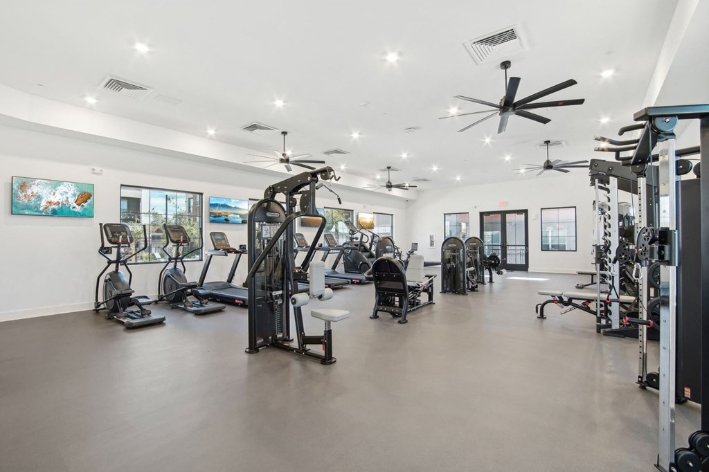 a gym with weights and cardio equipment in a building with white walls at The Maddox Luxury Apartment Homes, Buckeye Arizona