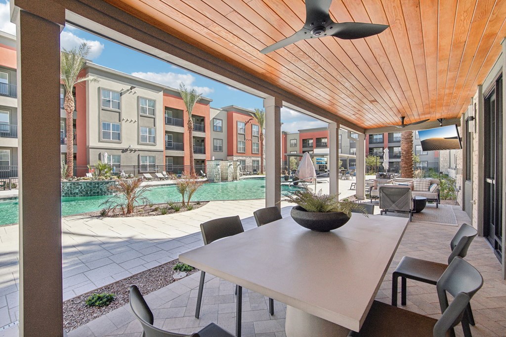 a patio with a table and chairs near a pool at The Maddox Luxury Apartment Homes, Buckeye, 85326