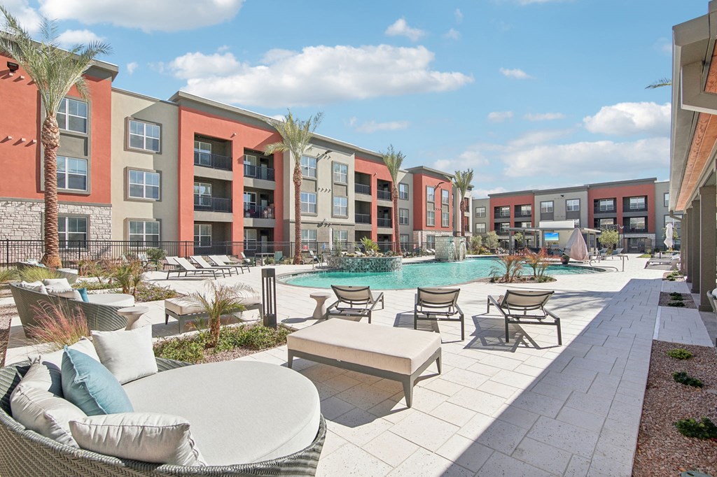 a pool with lounge chairs and tables in front of an apartment building at The Maddox Luxury Apartment Homes, Arizona, 85326