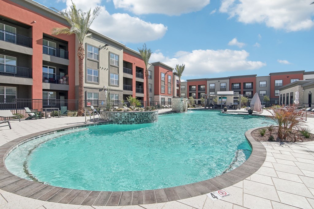 a swimming pool with an apartment building in the background at The Maddox Luxury Apartment Homes, Buckeye, AZ 85326