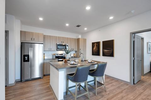 a kitchen with stainless steel appliances and a island with three chairs