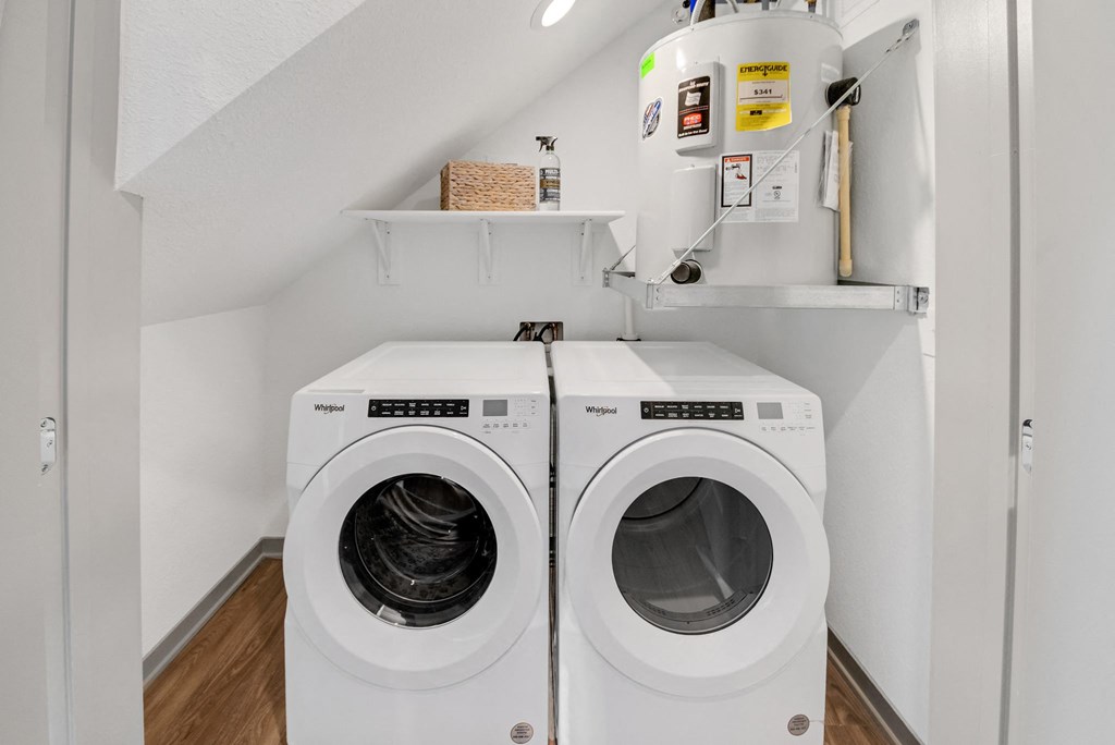 a washer and dryer in a laundry room with white walls and wooden floors at The BLVD at Wilson Crossings, Michigan