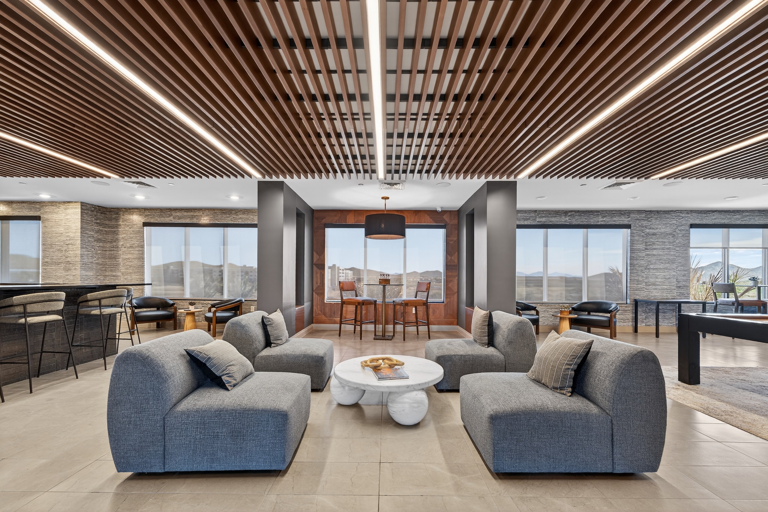A modern living room with grey couches and a wooden ceiling.