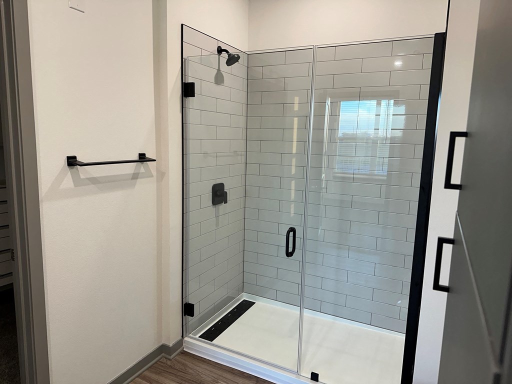 a white tiled shower in a bathroom with a glass door at The Depot, Missouri, 64083