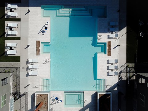 A swimming pool surrounded by lounge chairs and buildings.