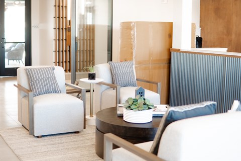 A modern living room with a grey couch, a white chair, and a wooden cabinet.