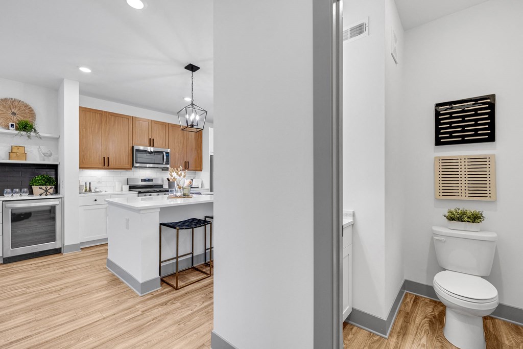 a white bathroom with a white toilet and a kitchen with wood floors at Meridian at CityPlace, Woodbury, 55125