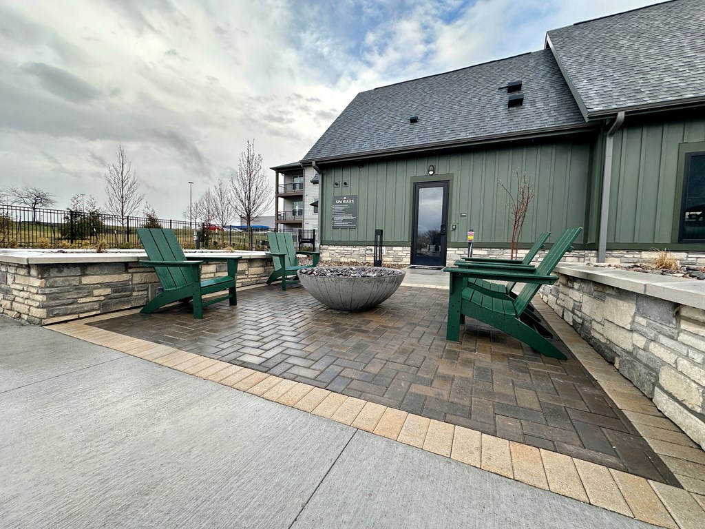 a patio with green chairs and a fire pit at The Depot, Raymore, MO