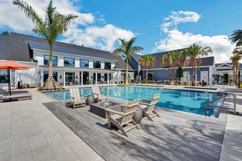 a swimming pool with lounge chairs and a coffee table in front of a building with palm trees  at The Sophia, Venice, FL