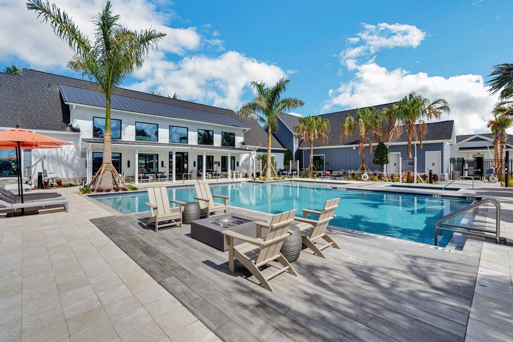 a swimming pool with lounge chairs and a coffee table in front of a building with palm trees  at The Sophia, Florida, 34275