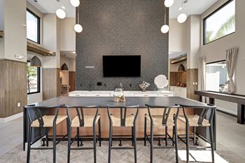 a large dining table with chairs in front of a kitchen with a large tv on the wall  at The Sophia, Venice, Florida