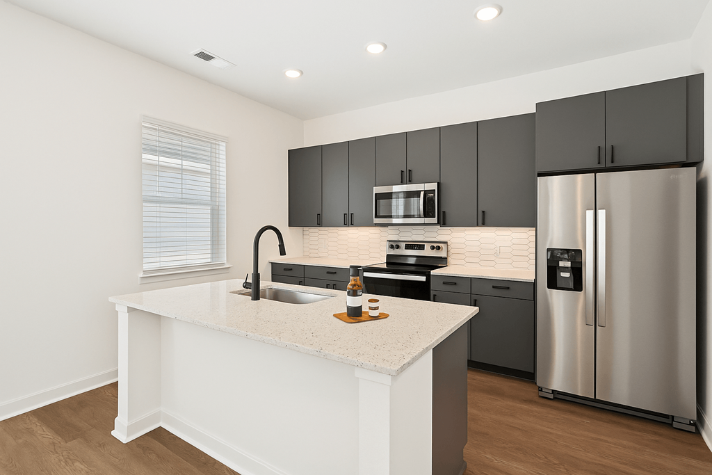 A modern kitchen with a white island and stainless steel appliances. at The Sophia, Venice, FL, 34275