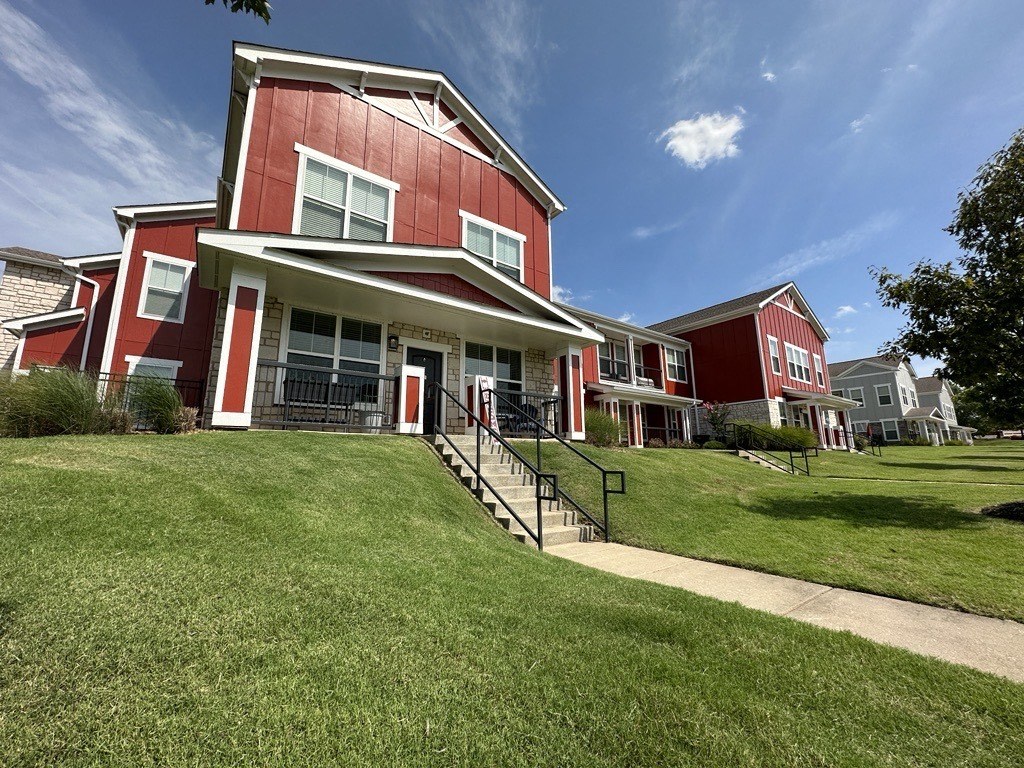 a row of red houses on a hill with green grass