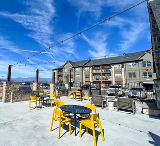 a patio with yellow chairs and tables and an apartment building