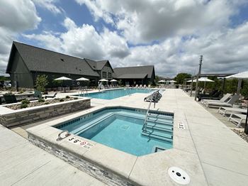 a swimming pool with chairs and a building in the background