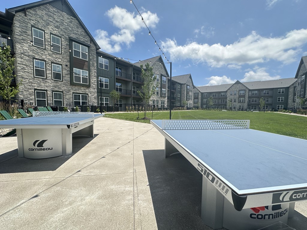 two ping pong tables with an apartment building in the background