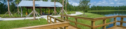 A wooden deck overlooks a lake with a pavilion in the background at Velara Luxury Apartments, Florida, 32081