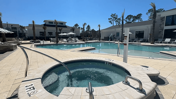 A large outdoor swimming pool with a hot tub in the middle at The Quinn Luxury Apartments, Pensacola, Florida