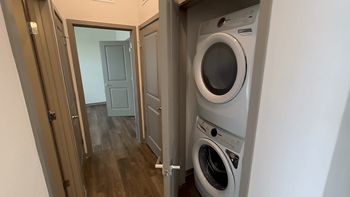 A washing machine is in a small room with a door open.