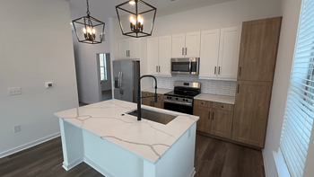 A kitchen with a white island and wooden cabinets.