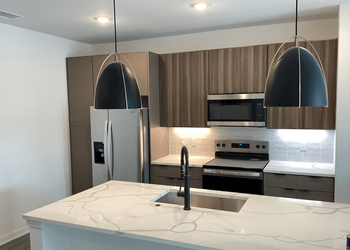 A modern kitchen with a marble countertop and stainless steel appliances at The Stadler Luxury Apartments, Florida 34210