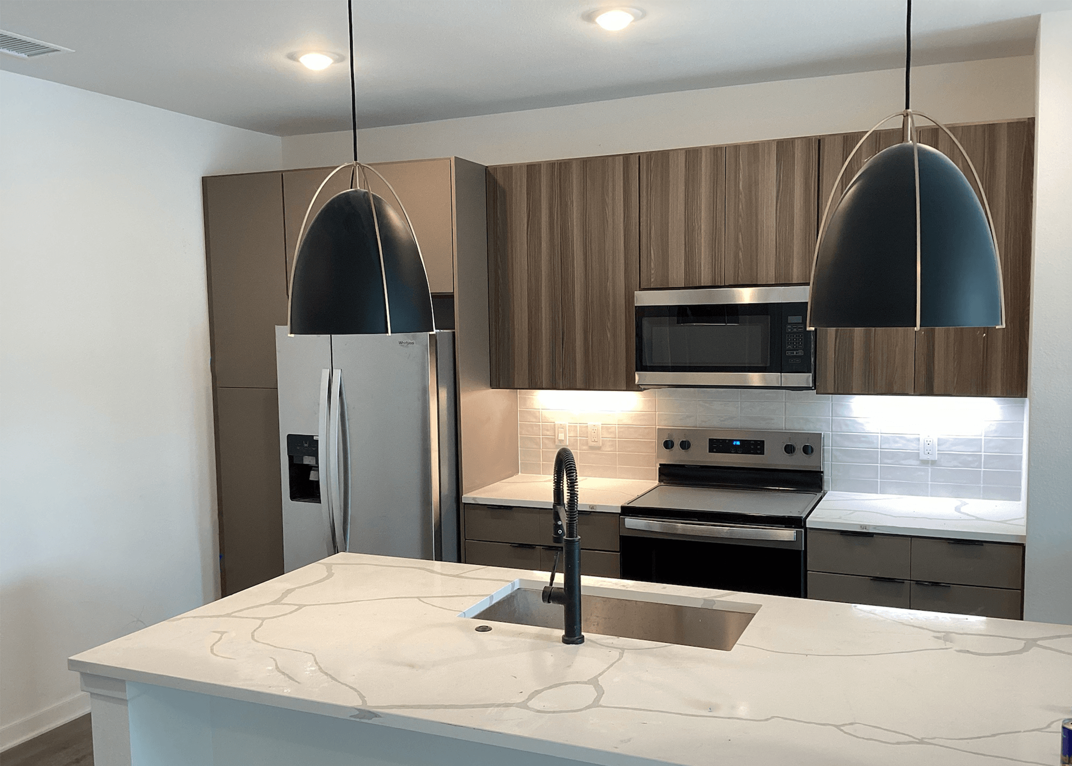 A modern kitchen with a marble countertop and stainless steel appliances.