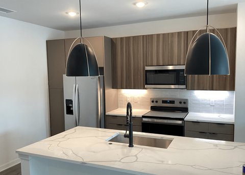 A modern kitchen with a marble countertop and stainless steel appliances  at The Stadler Luxury Apartments, Bradenton, Florida