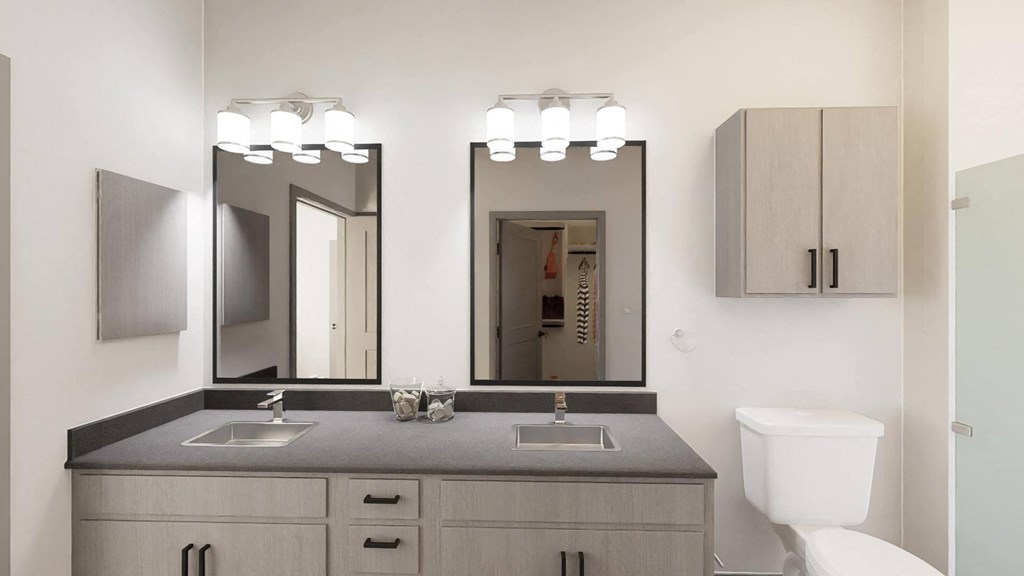 a bathroom with a sink and two mirrors and a toilet at Stella, San Tan Valley
