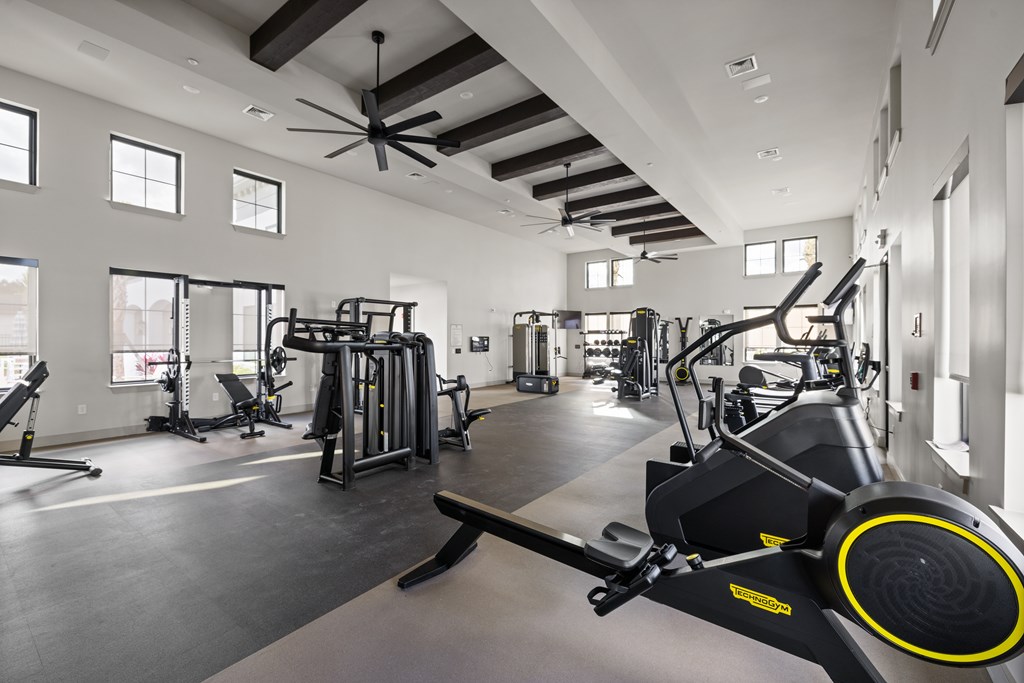 A spacious gym with a variety of equipment including treadmills, weights, and a rowing machine.