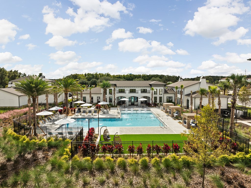 A pool surrounded by a black fence with trees and bushes in the foreground.