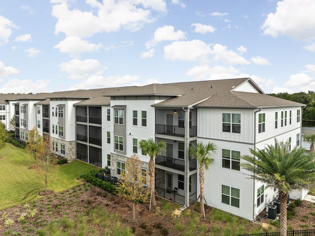 A white apartment building with balconies and a green lawn in front.