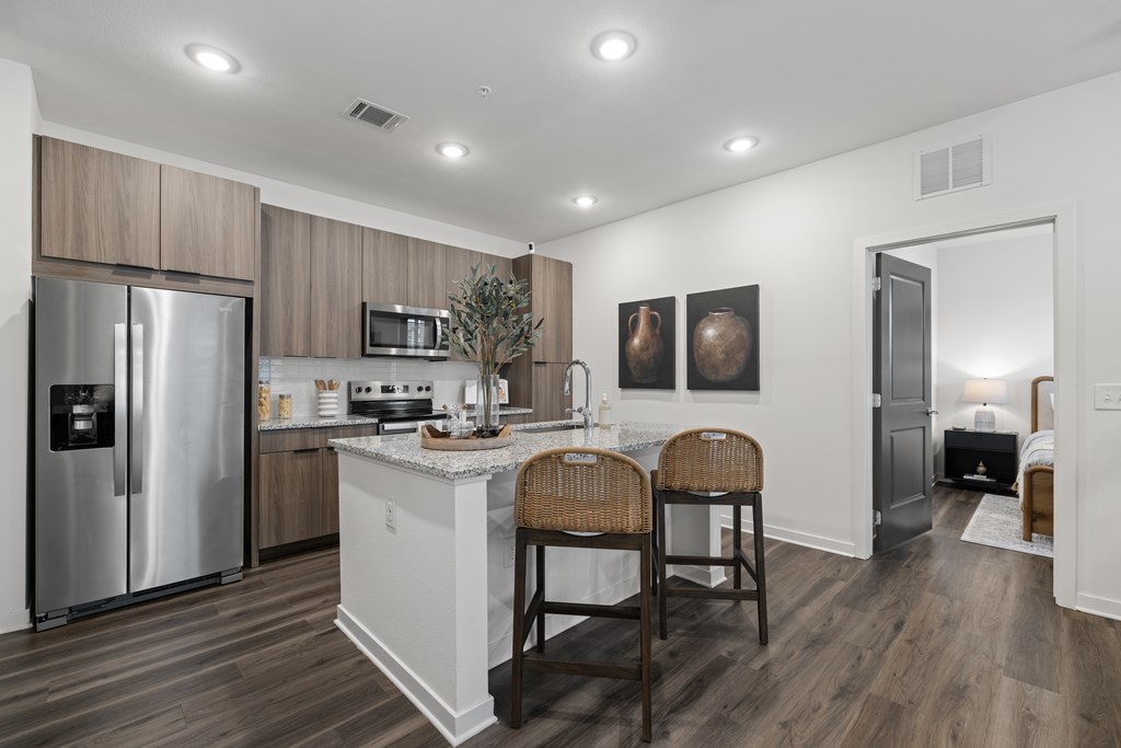 A kitchen with a refrigerator, microwave, and a counter with a plant on it.