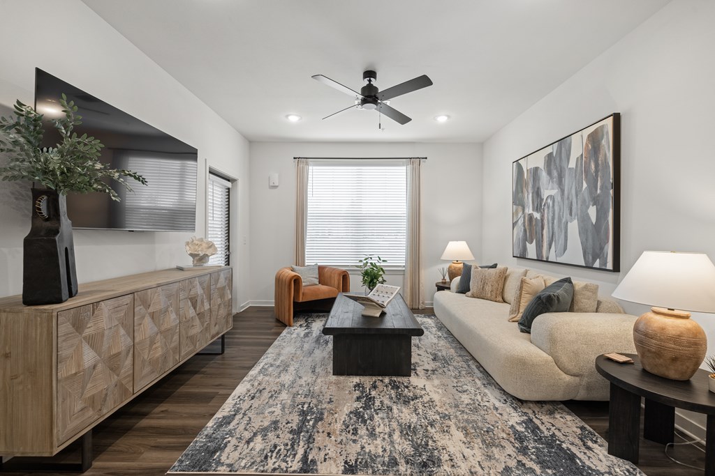 A living room with a rug, a couch, a coffee table, and a ceiling fan.