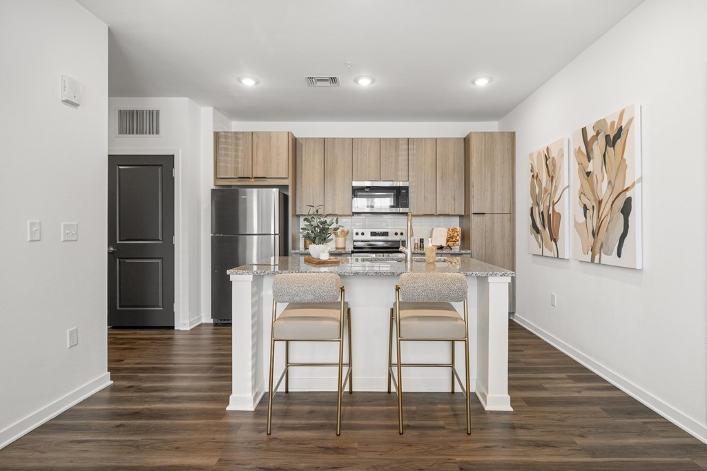 A kitchen with a white island and two chairs.
