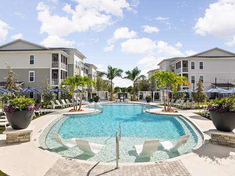 A swimming pool surrounded by white chairs and potted plants.