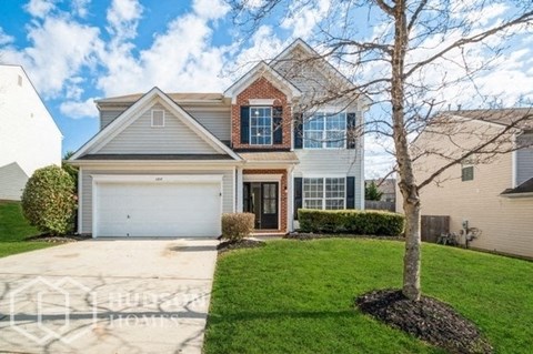 a white house with a garage and a tree in front of it