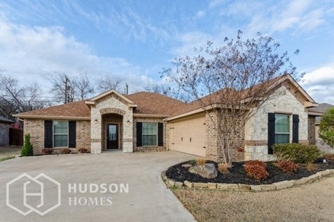 a brick house with a driveway and a tree in the front