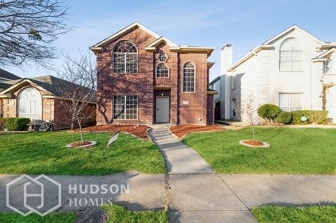 a brick house with a sidewalk in front of it