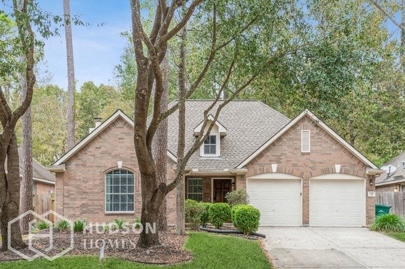 a brick house with two garage doors and trees